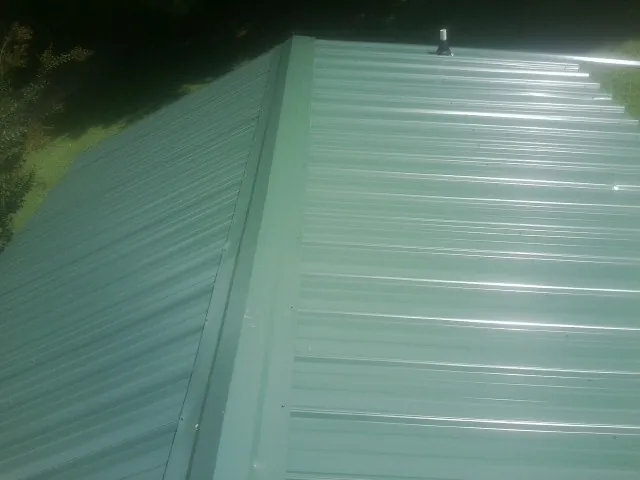 New green metal panels meeting at the ridge of a roof — Flat Roof Repair work by our crew in Daleville