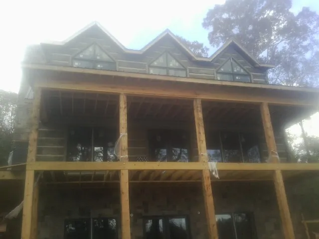 Dormers and porch framing on a large log home under construction — Roof Coating work by our crew in Daleville