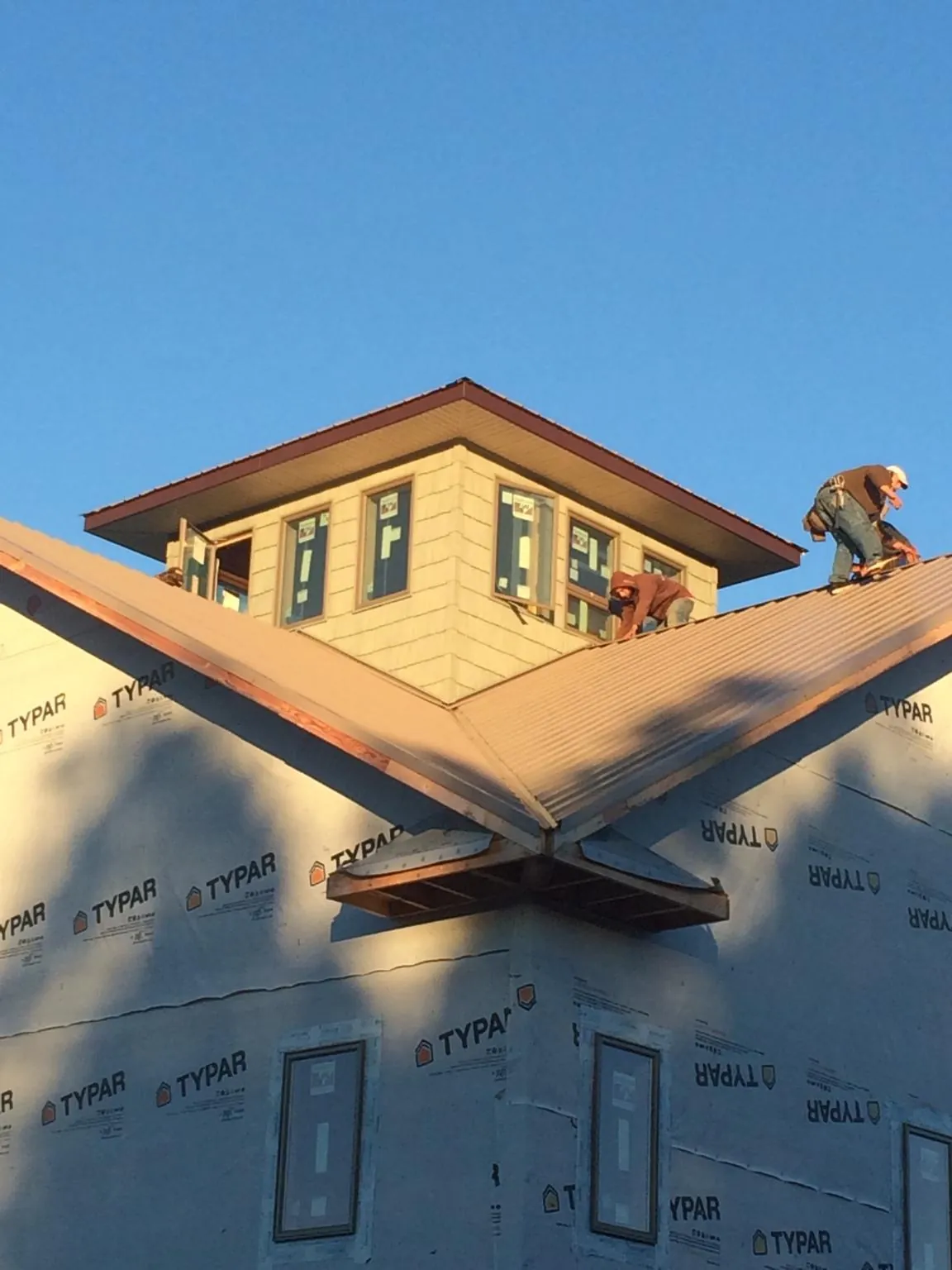 Roofers working around a rooftop cupola on a new metal roof at sunset — Roof Waterproofing in Daleville by Roofing Brothers